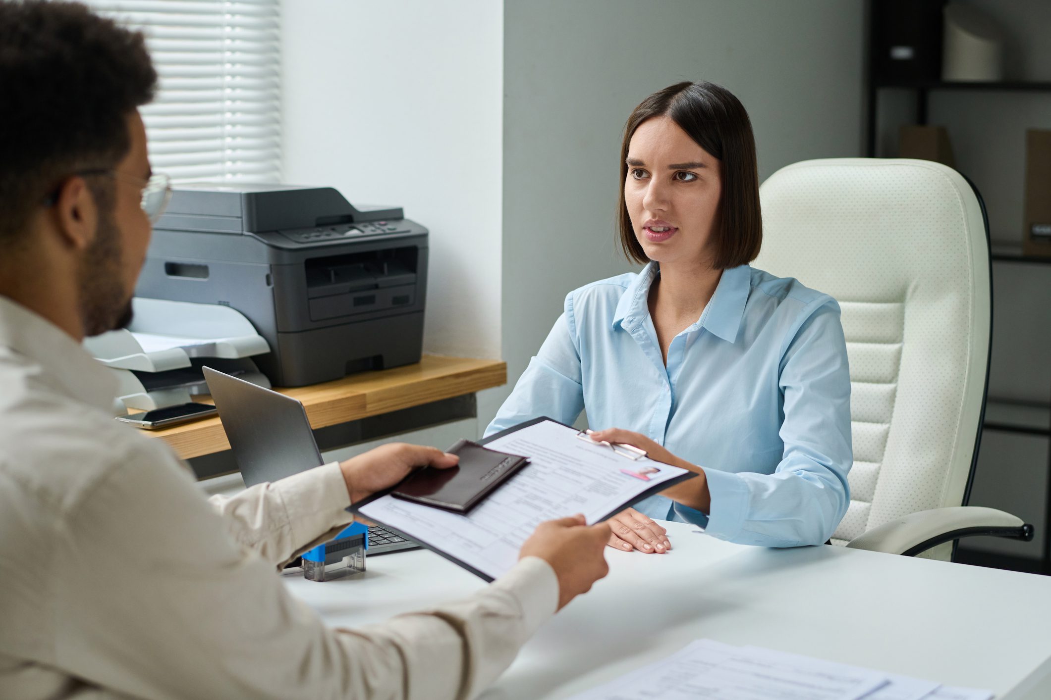 Man giving documents to get visa Specialist talking to man while he giving document to get visa