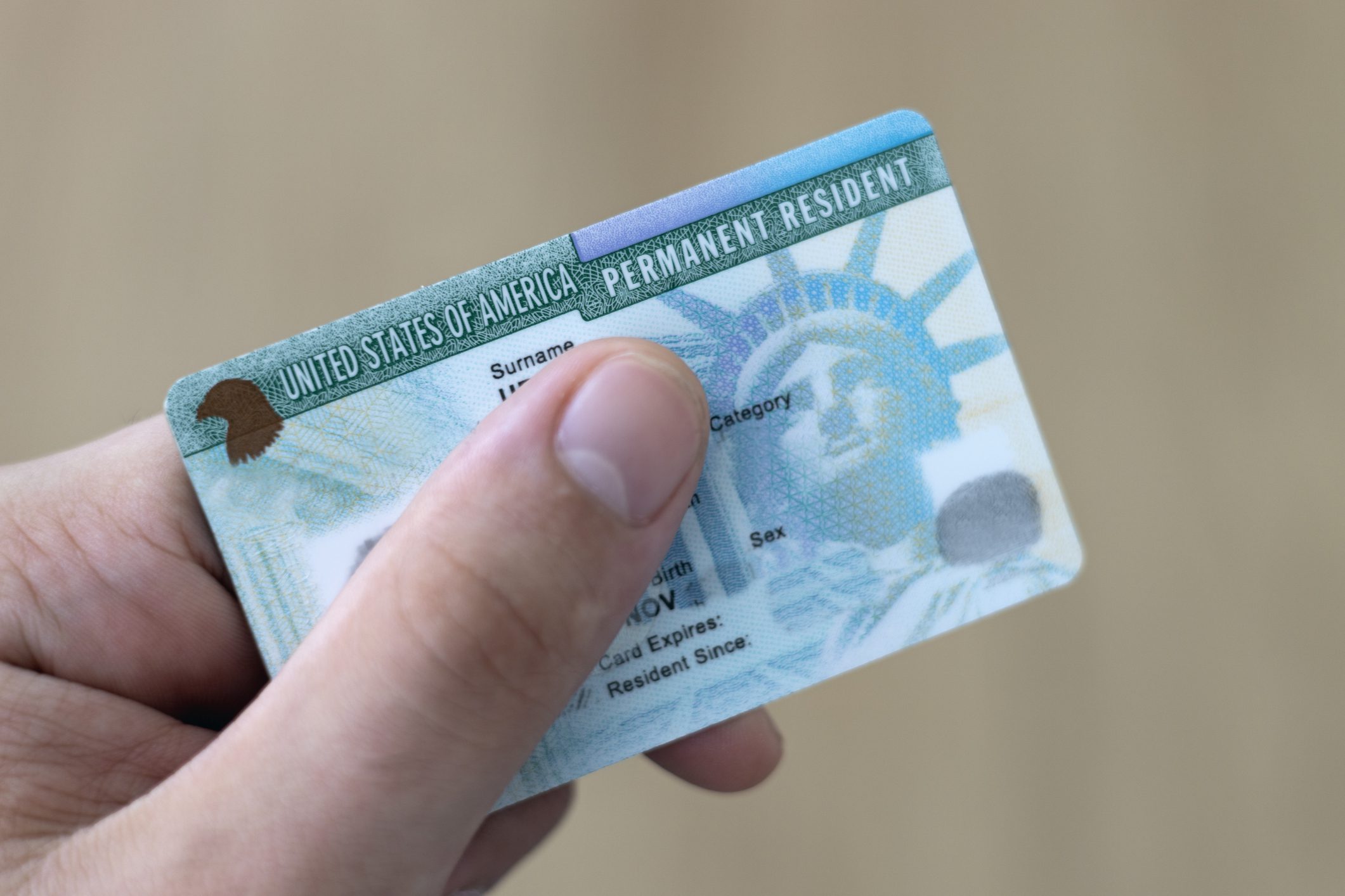Man holding US permanent resident (green) with his hand. Immigration concept Man holding US permanent resident (green) with his hand. Immigration concept