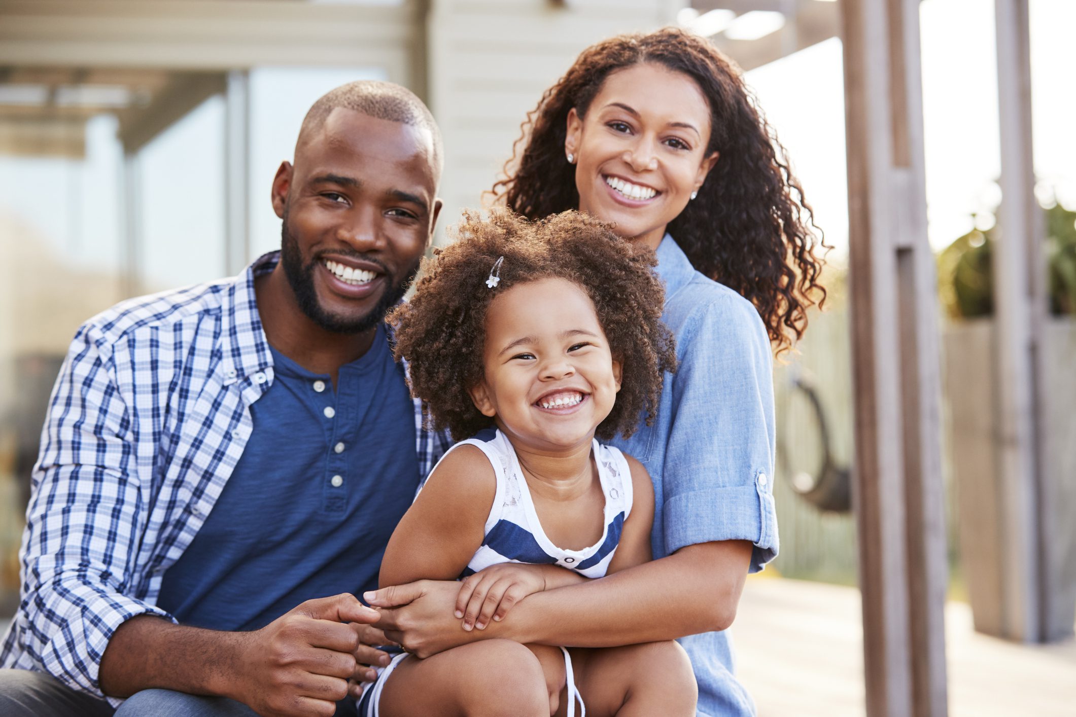 Young black family embracing outdoors and smiling at camera Young black family embracing outdoors and smiling at camera